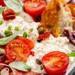 A close up of burrata salad on a platter.