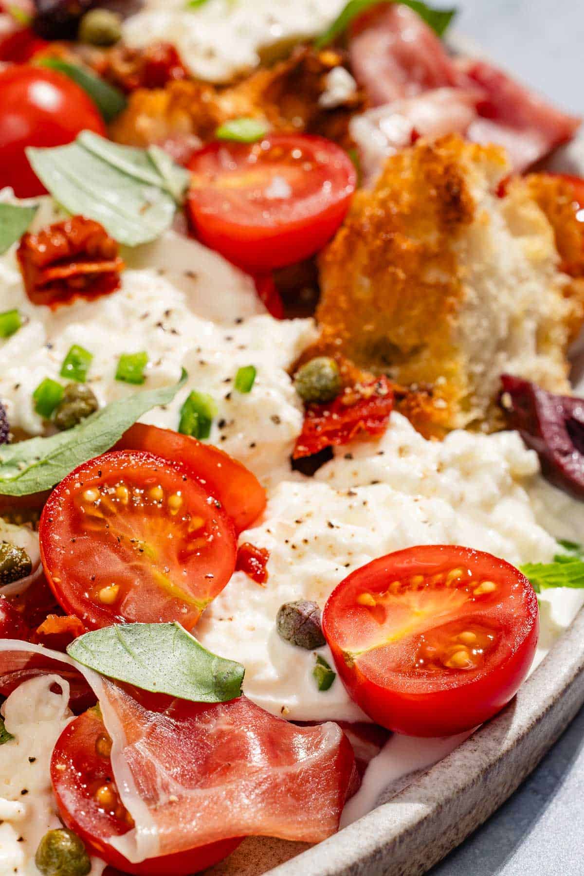 A close up of burrata salad on a platter.