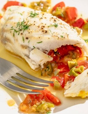 A close up of a stuffed flounder fillet on a plate with a fork.