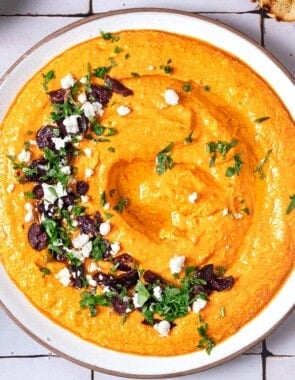 Overhead shot of Tirokafteri Spicy Greek Feta Dip with a feta, parsley, and olive garnish.