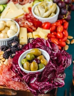 close up of a large antipasto platter with a selection of meats, cheeses, fruits, vegetables and nuts.