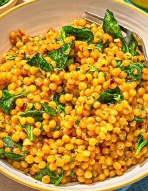 Spinach couscous in a bowl with a fork.