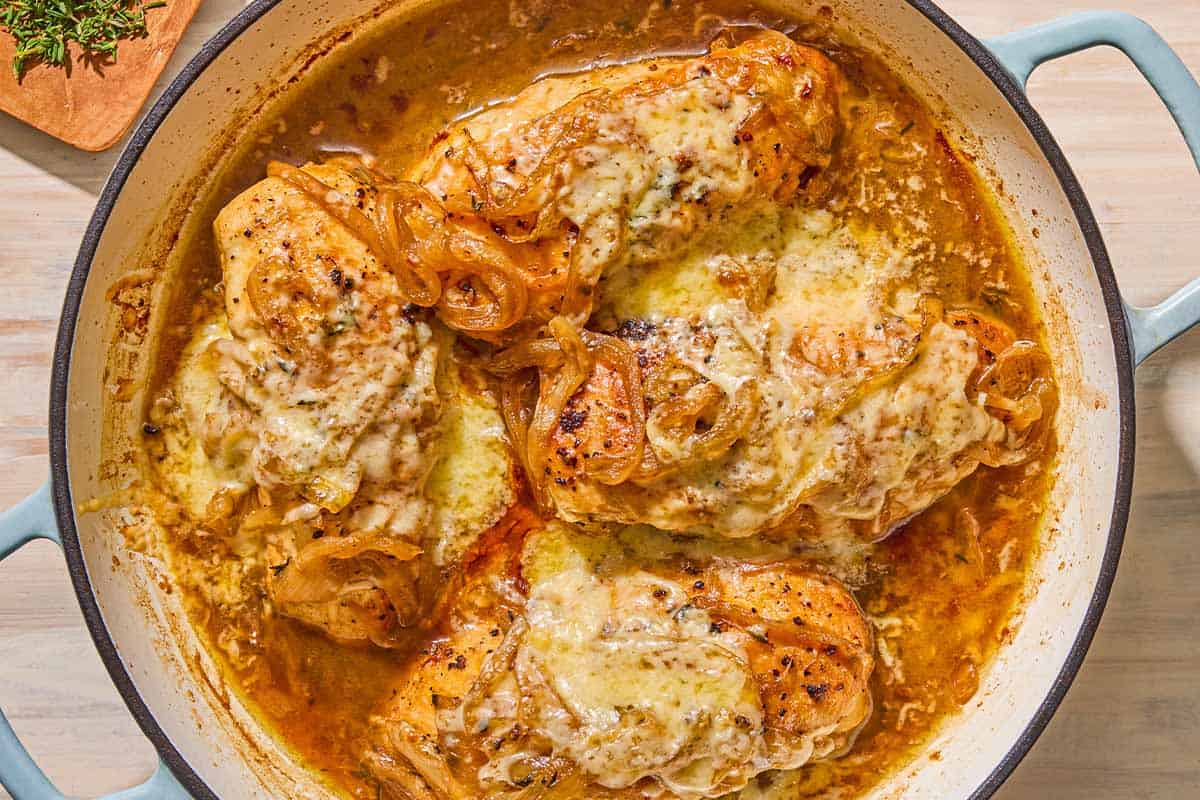 French onion chicken in a skillet next to a bowl of chopped thyme.
