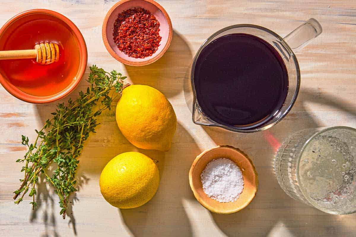Ingredients for the tart cherry mocktail including tart cherry juice, club soda, lemon, fresh thyme, honey, aleppo pepper and sea salt.