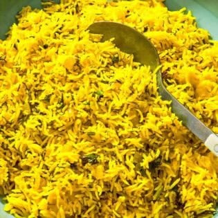 Turmeric rice in a serving bowl with a spoon.