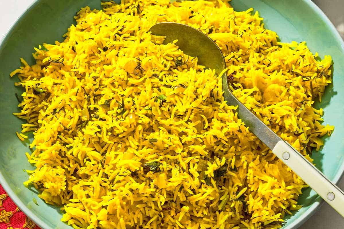 Turmeric rice in a serving bowl with a spoon.