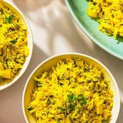 Three bowls of turmeric rice and a bottle of olive oil.