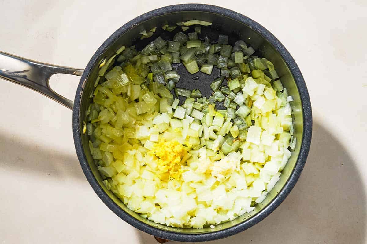 The chopped onions and other aromatics for the turmeric rice being sautéed in a saucepan.