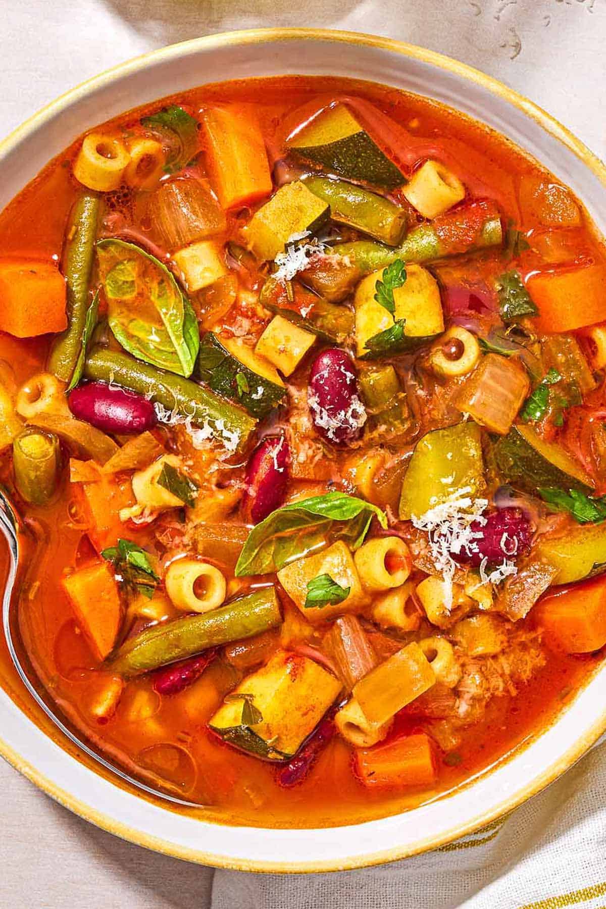 Minestrone soup in a bowl with a spoon.